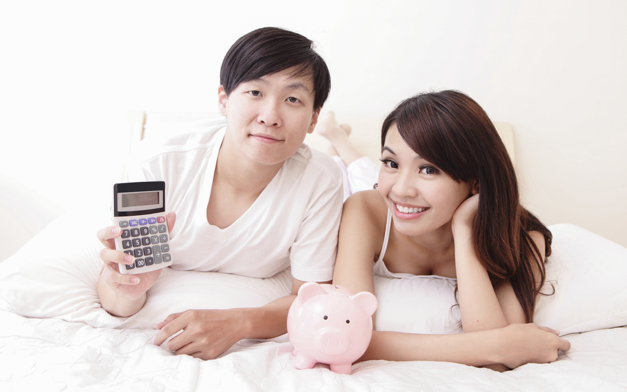 happy couple with pink piggy bank and calculator